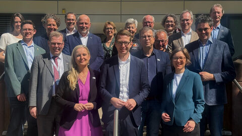 Gruppenfoto einer gemischten Personengruppe vor einem modernen Gebäude.