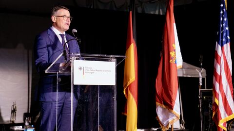 Ministerpräsident Rhein steht auf der Bühne und spricht in ein Mikofron