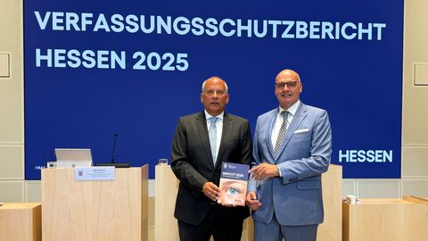Zwei Männer stehen in Anzügen nebeneinander