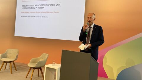 Bildungsminister Armin Schwarz Mann steht auf einer Bühne und spricht in ein Mikrofon.