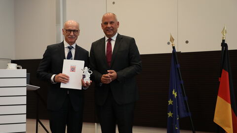 Innenminister Roman Poseck verabschiedet Landespolizeipräsident Robert Schäfer in den Ruhestand Zwei Männer stehen nebeneinander in einem Raum.