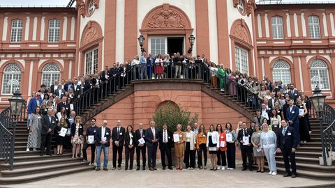 Innenminister Roman Poseck bei der Verleihung des Gütesiegels „Familienfreundlicher Arbeitgeber Land Hessen“ und „Familienfreundliche Hochschule Land Hessen“ Innenminister Roman Poseck sowie zahlreiche Gäste stehen vor dem Schloss Biebrich Wiesbaden