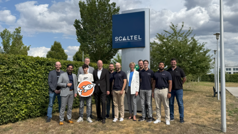 Praktikumstag bei der Scaltel Mehrere Personen stehen auf einer Wiese und schauen in die Kamera. Hinter ihnen ist das Logo des Unternehmens Scaltel zu sehen